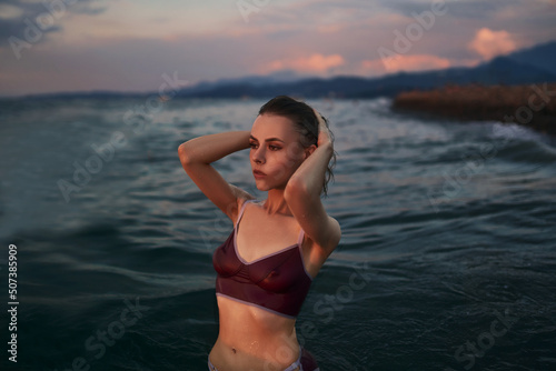 Gorgeous slim model in a violet swimsuit is posing in the water.