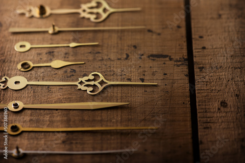 Clock hands or needle aligned on old wooden surface. Time concept image. Focus on center needle. Shallow depth of field.