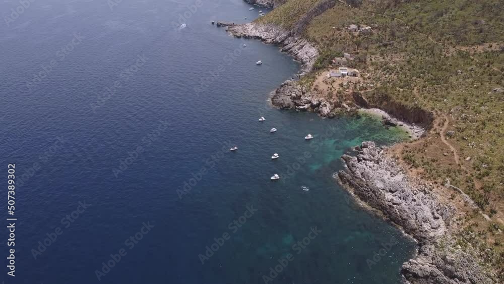 Aerial drone view above the beautiful coastline, turquoise clear sea water and wild nature of Zingaro Nature Reserve, Sicily. Tropical travel holiday destination in Europe near Scopello in Italy. Aerial drone view above the beautiful coastline, turquoise clear sea water and wild nature of Zingaro Nature Reserve, Sicily. Tropical travel holiday destination in Europe near Scopello in Italy.