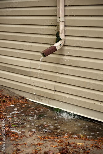 Rain Water Pours Out of a Short Downspout on side of house pooling by foundation