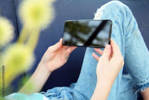 Teen girl is checking social media holding smartphone outside.