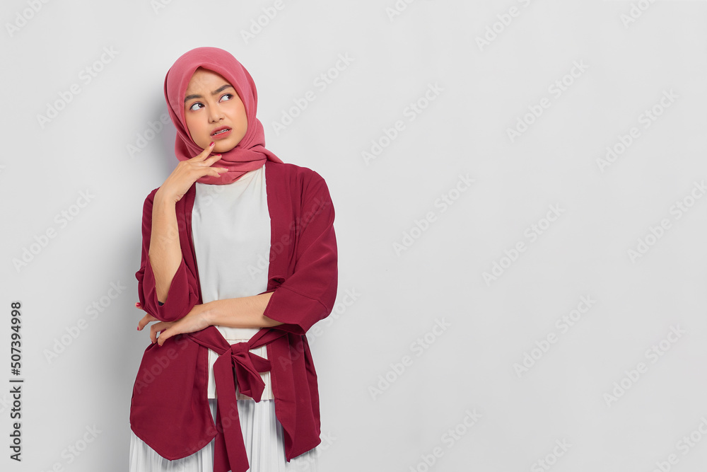 Pensive beautiful Asian woman in casual shirt thinking about something and looking away isolated over white background