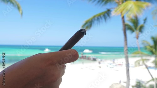 Cuban cigar with smoke in male hand, closeup. Luxury vacations photo