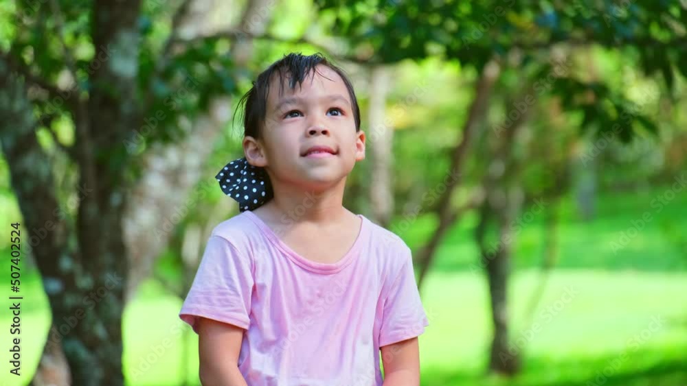 Cute little Asian girl playing with a smile in nature. Happy young girl enjoying nature in spring garden. Freedom and imagination concept Cute little Asian girl playing with a smile in nature. Happy young girl enjoying nature in spring garden. Freedom and imagination concept