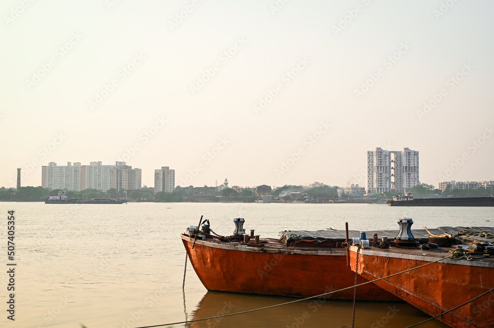 TWO red boat floating on Ganges river near Princep Ghat Kolkata under the sun.