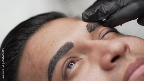 Close up shot of male microblading procedure to making permanent eyebrows makeup photo