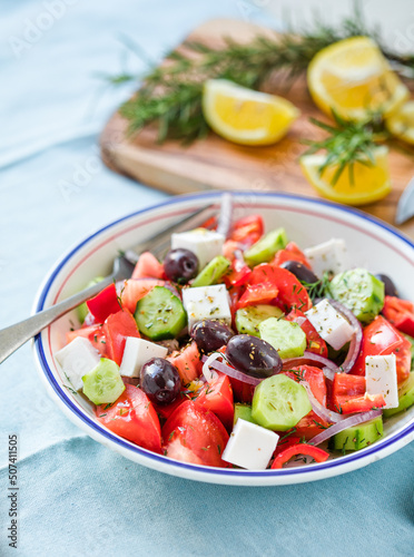 Greek salad with feta cheese, olives, tomato, cucumber and red onion, healthy vegeterian mediterranean diet food, low calories eating. Blue fabric background, top view