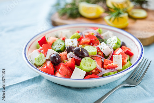 Greek salad with feta cheese, olives, tomato, cucumber and red onion, healthy vegeterian mediterranean diet food, low calories eating. Blue fabric background, top view © Maria