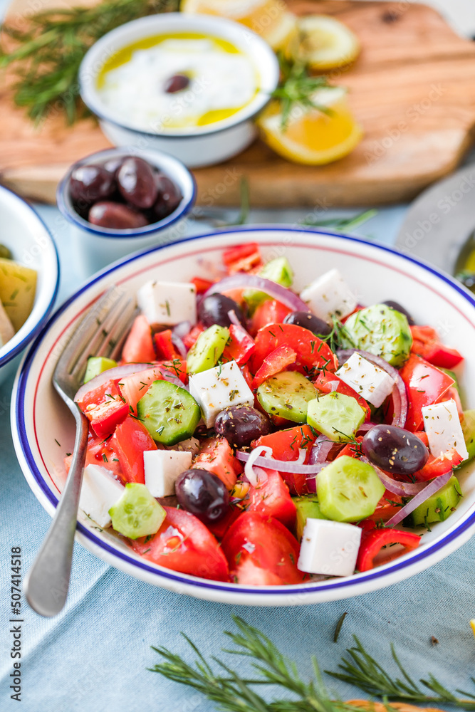 Greek salad with feta cheese, olives, cherry tomato, paprika, cucumber and red onion, healthy vegeterian mediterranean diet food, low calories eating. White stone background, top view