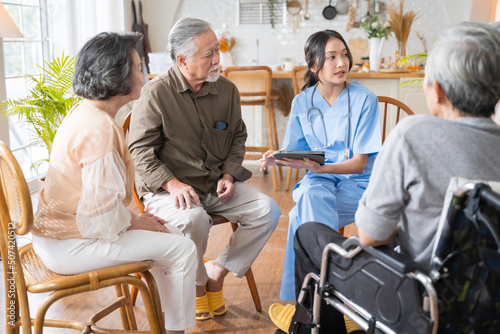 Group of Asian senior people sit in a circle in a nursing home and listen to nurse during a group elderly therapy session.