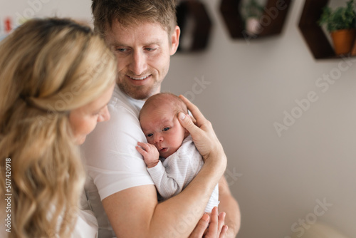 Happy mother and father holding their newborn baby daughter at home