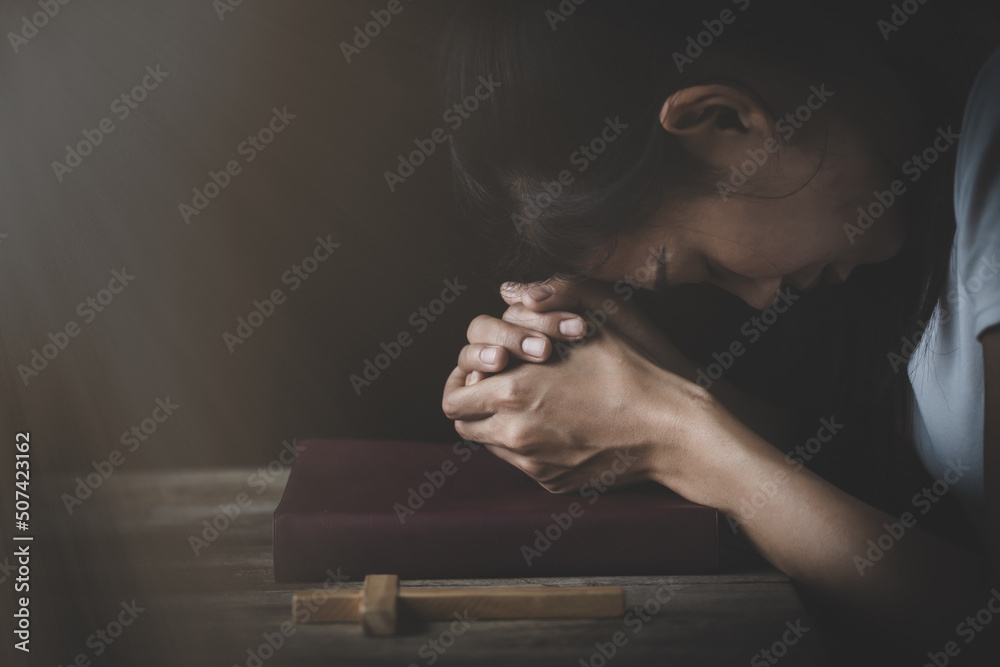The hand placed on the Bible with his head bowed down. Pray to God. Praying for spiritual beliefs. The power of hope or love and loyalty. Faith in goodness. - obrazy, fototapety, plakaty 