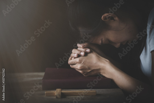 The hand placed on the Bible with his head bowed down Fototapeta