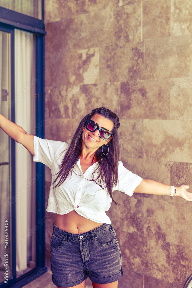 Fototapeta premium Beautiful Smiling Happy brunette Woman enjoying vacation relaxing at luxurious beachfront villa near a private pool taking a coffe 