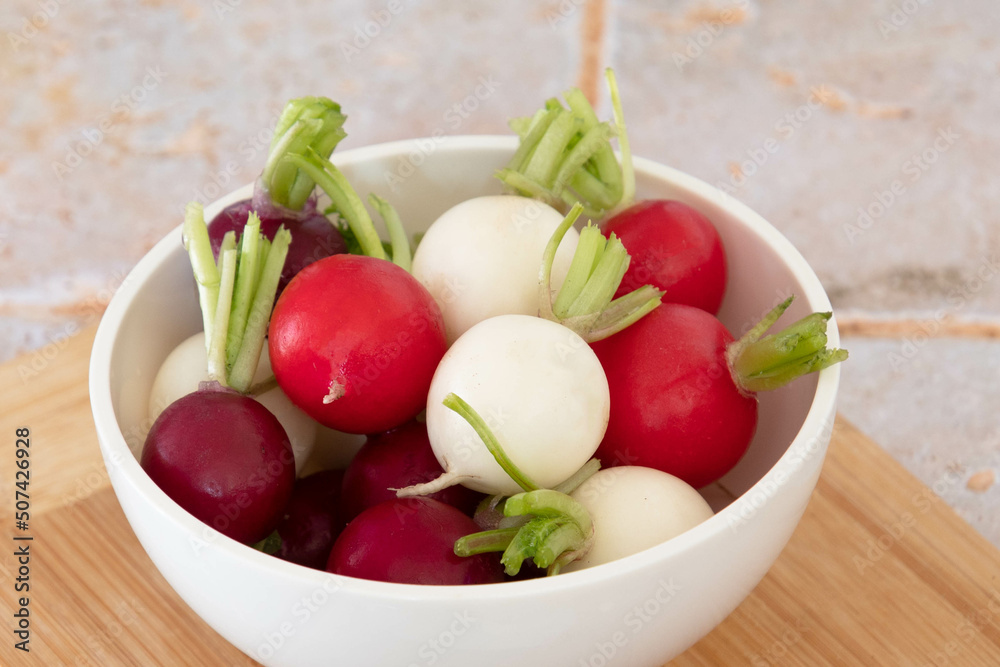 close up of tricolor radishes in a bowl on a table