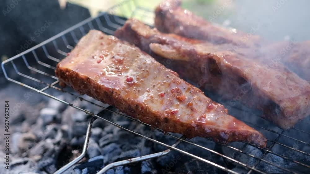 delicious beef or pork ribs frying on a charcoal grill 