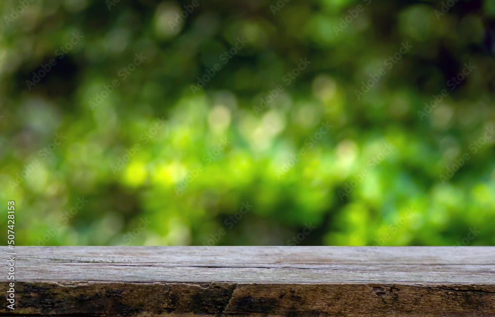 Old wood empty table for product display in front of green and yellow bokeh abstract background Old wood empty table for product display in front of green and yellow bokeh abstract background