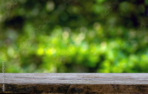 Old wood empty table for product display in front of green and yellow bokeh abstract background