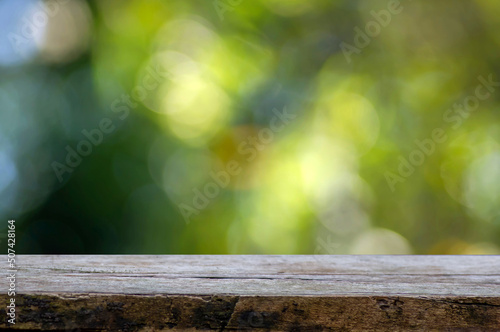 Old wood empty table for product display in front of green and yellow bokeh abstract background