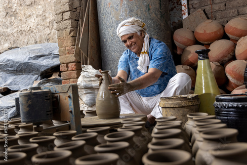 Photography Skilled hands of a potter shaping the clay into pot on spinning wheel