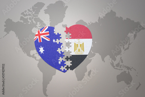 puzzle heart with the national flag of egypt and australia on a world map background. Concept.