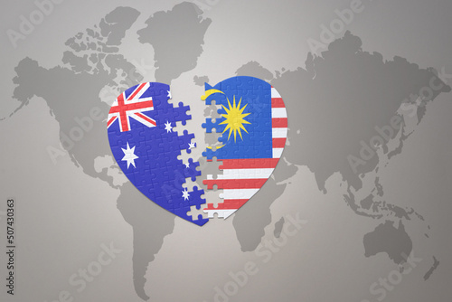 puzzle heart with the national flag of malaysia and australia on a world map background. Concept.