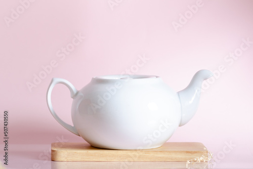 White teapot on pink background.