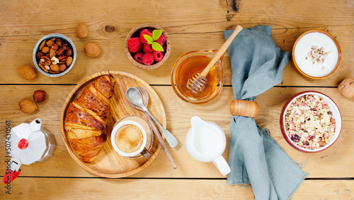 Typical Italian breakfast with a cup of espresso, croissants, raspberry,  muesli, nuts, milk, yogurt on wooden background. photo