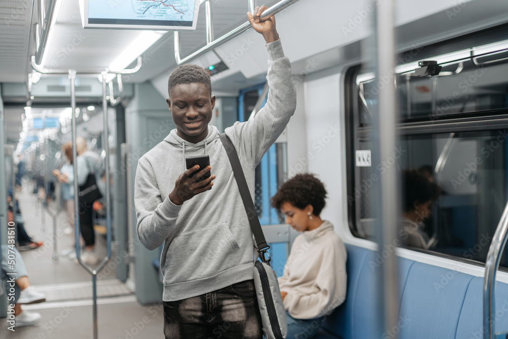 smiling guy with a smartphone standing in a subway car . smiling guy with a smartphone standing in a subway car .