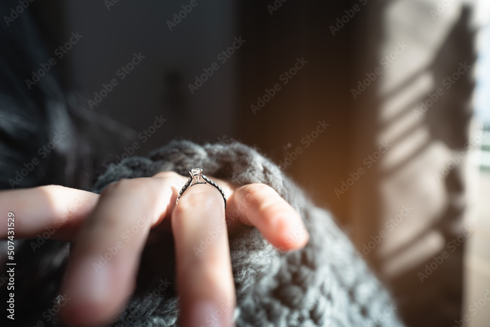 Close up of an elegant engagement diamond ring on woman finger with dark gray sweater winter clothe. love and wedding concept. Soft and selective focus. Close up of an elegant engagement diamond ring on woman finger with dark gray sweater winter clothe. love and wedding concept. Soft and selective focus.