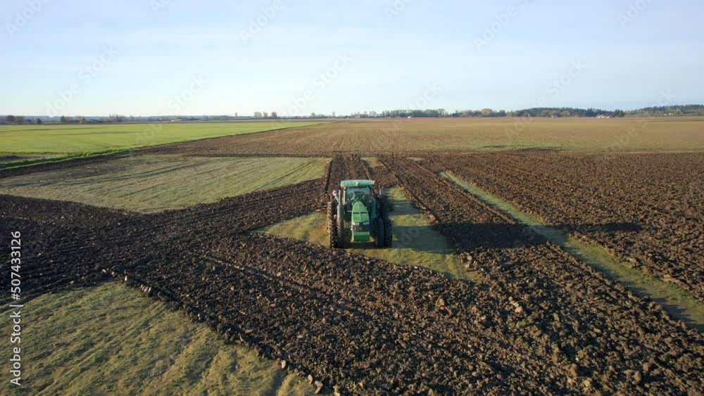 Aerial video of green tractor plowing a field in the spring to get ready for planting Aerial video of green tractor plowing a field in the spring to get ready for planting