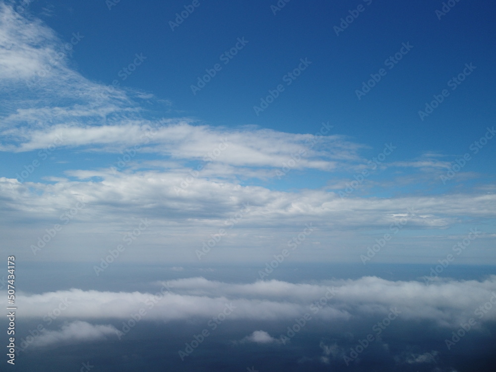 Aerial view. Blue sky sun and fog over calm sea. The drone flies over foggy and fluffy clouds. Abstract aerial nature summer ocean sunset sea and sky background. Vacation, travel and holiday concept.