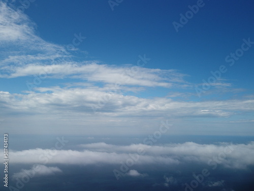 Aerial view. Blue sky sun and fog over calm sea. The drone flies over foggy and fluffy clouds. Abstract aerial nature summer ocean sunset sea and sky background. Vacation, travel and holiday concept. © panophotograph