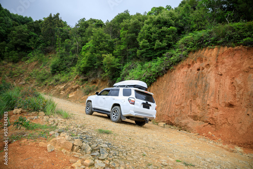 Driving off road car in tropical forest mountains