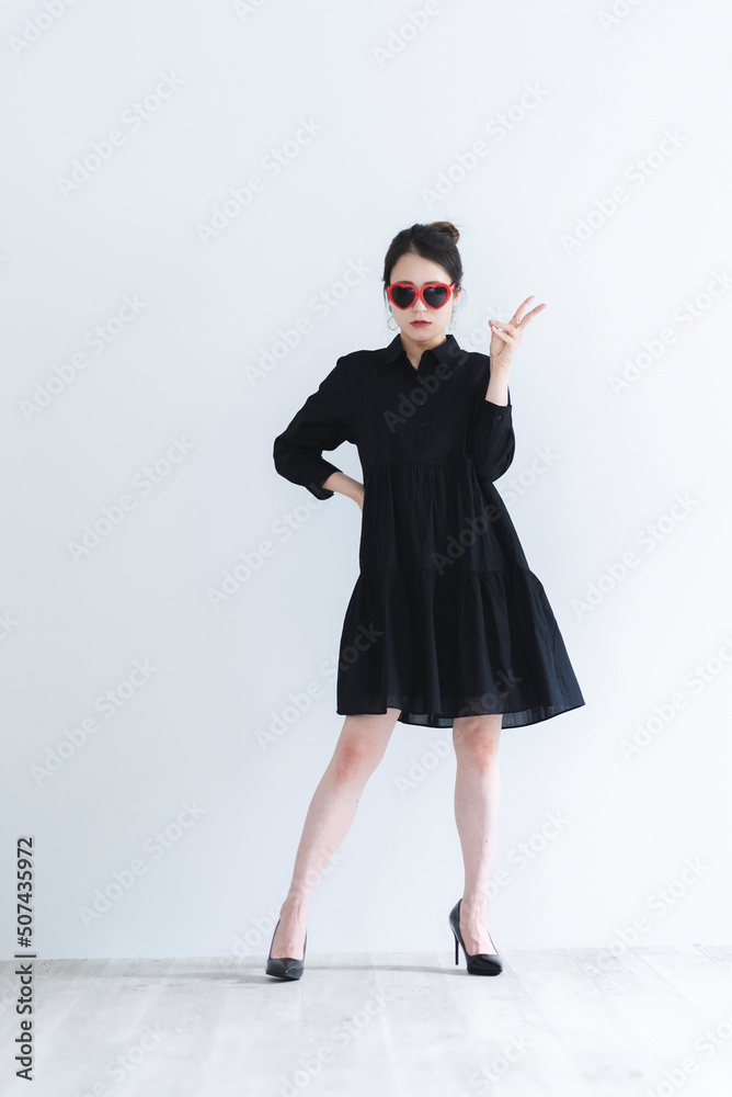 ハートのサングラスをかけて黒いワンピースを着たクールな女性 ハートのサングラスをかけて黒いワンピースを着たクールな女性