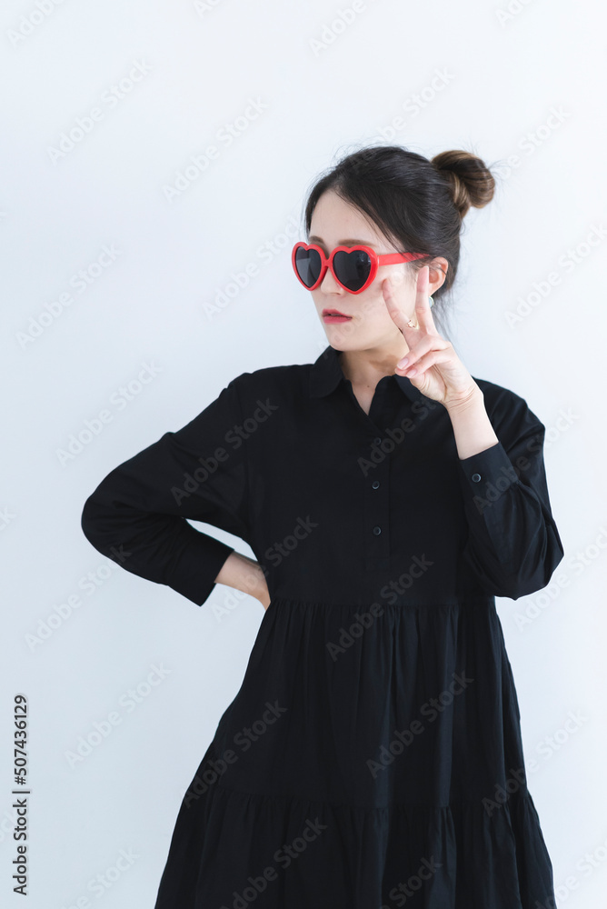 ハートのサングラスをかけて黒いワンピースを着たクールな女性 ハートのサングラスをかけて黒いワンピースを着たクールな女性