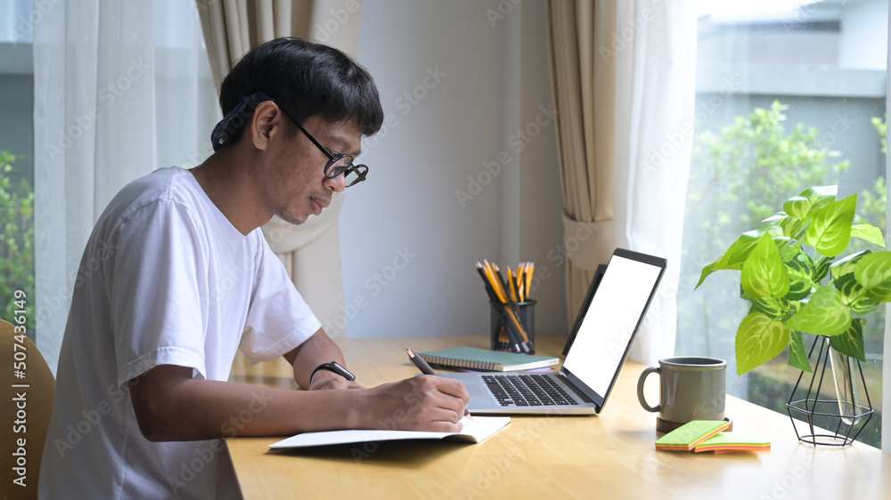 Concentrated asian man working online from home with computer laptop Concentrated asian man working online from home with computer laptop