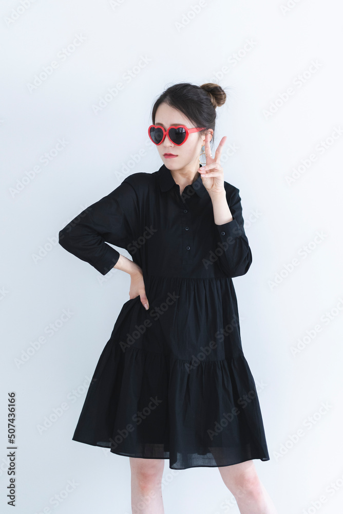 ハートのサングラスをかけて黒いワンピースを着たクールな女性 ハートのサングラスをかけて黒いワンピースを着たクールな女性