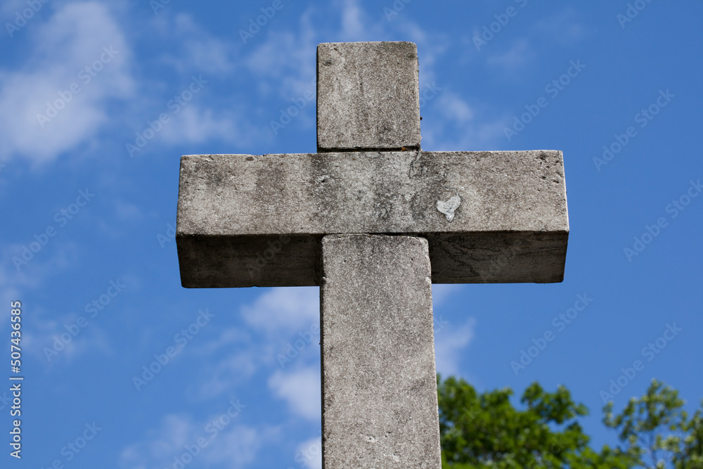 A cross made of granite against a blue sky.