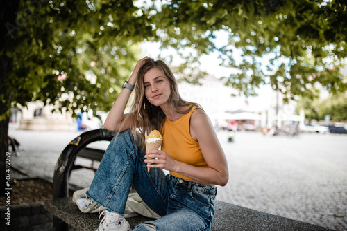 Young woman with light brown hair is enjoying summer and posing with yummy gelato. © Michaela