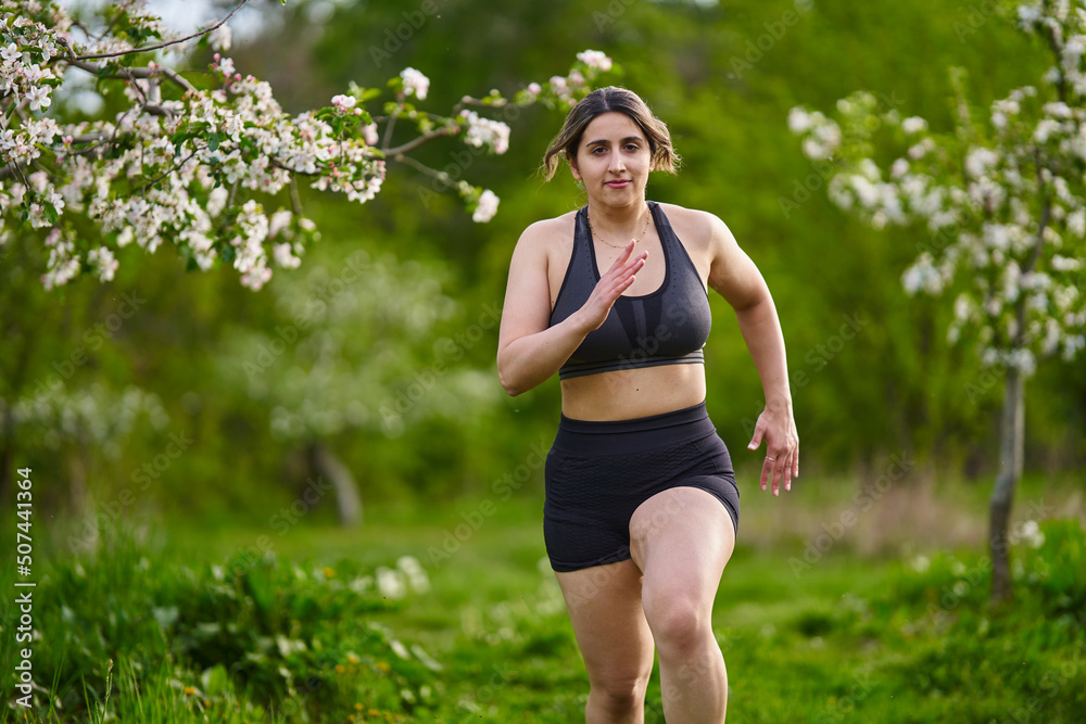 Plus size lady running through an orchard Plus size lady running through an orchard