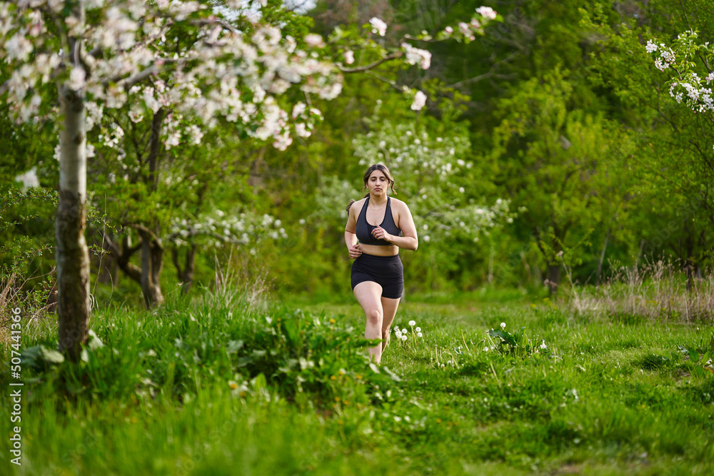 Plus size lady running through an orchard Plus size lady running through an orchard