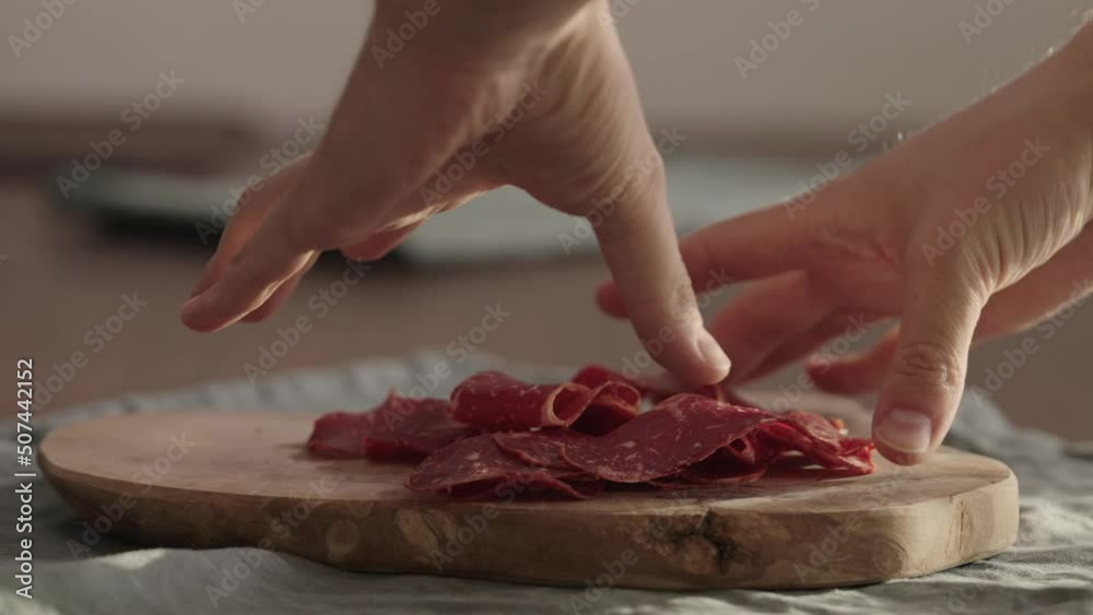 Slow motion man hands picking pastrami from olive wood board closeup Slow motion man hands picking pastrami from olive wood board closeup