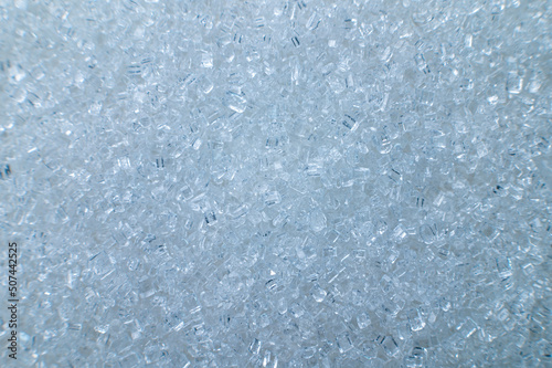 Macro shot of white sugar closeup on the surface as an abstract background. Food industry benefits and harms of granulated sugar
