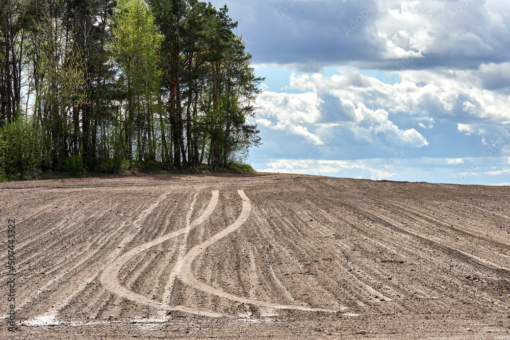 Agricultural work in the spring. Spring landscape. spring field sky with clouds and forest Agricultural work in the spring. Spring landscape. spring field sky with clouds and forest