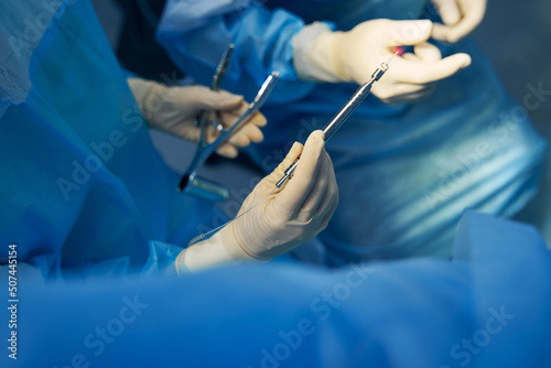 Nurse passing electrosurgical pencil to operating surgeon
