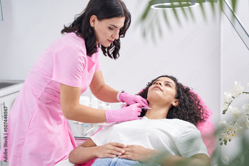 Woman doctor injecting into the neck of a young patient Woman doctor injecting into the neck of a young patient