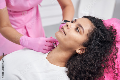 Medical worker injecting into the neck of a young patient photo