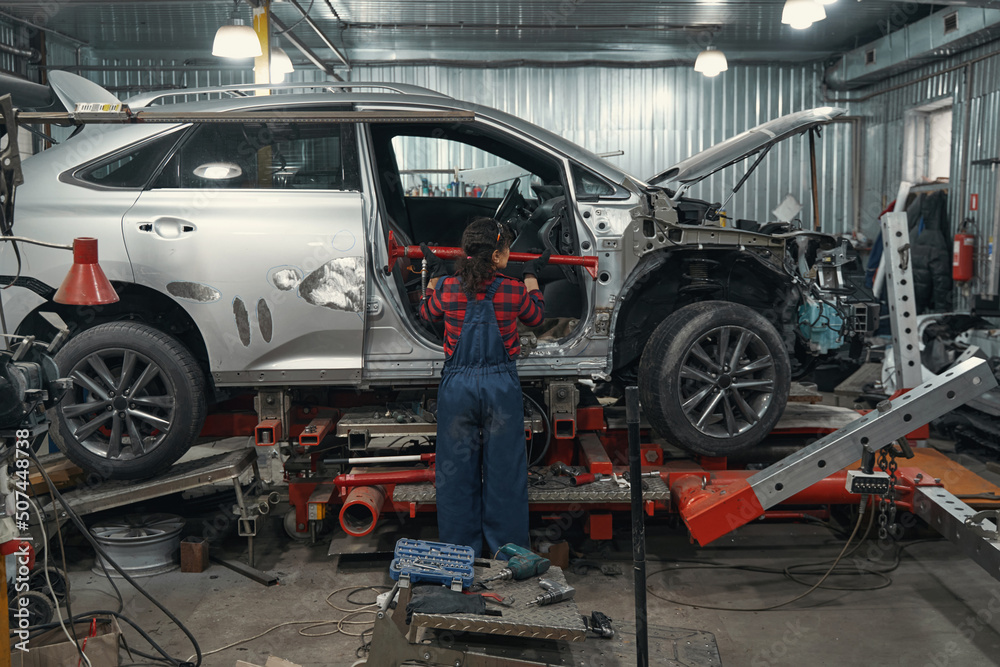 Female auto mechanic repairing vehicle in car garage
