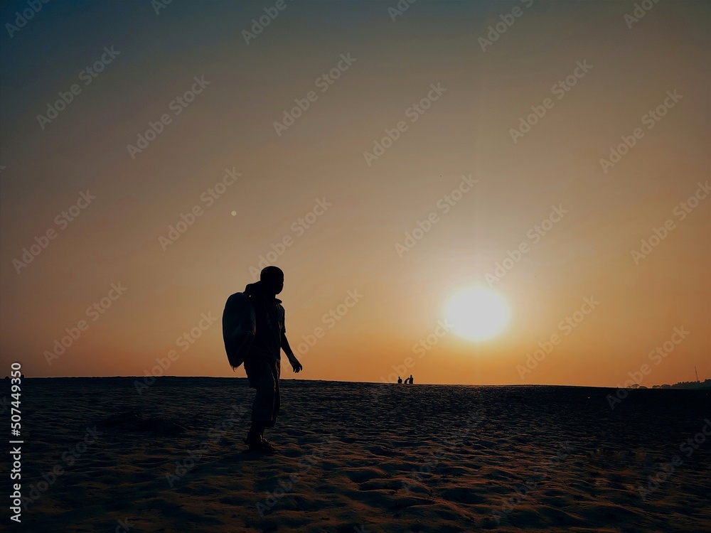Fototapeta premium The sunset with the boy when walking in the sand desert of Padma. 
